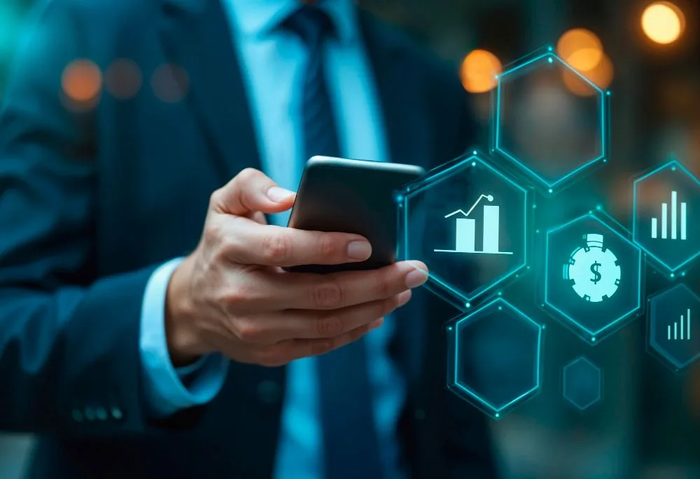 Ejecutivo con traje sosteniendo un smartphone con gráficos y datos flotantes, representando aplicaciones corporativas para empresas