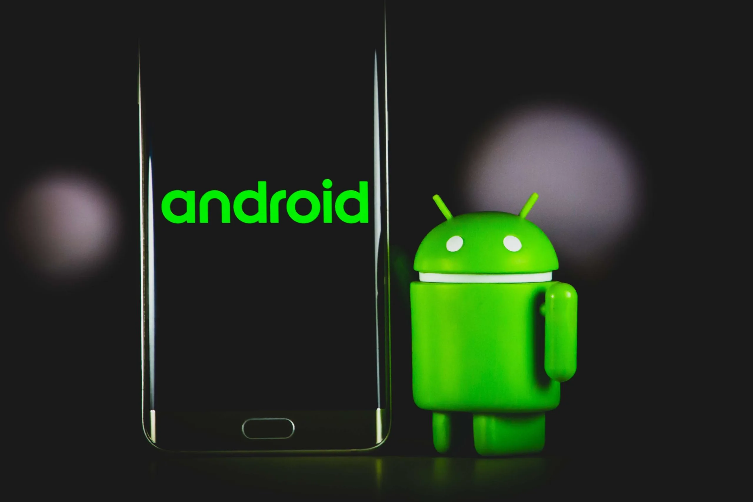 Figura del robot Android verd al costat d'un smartphone amb el logo Android