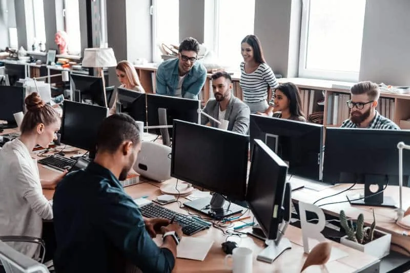 Desenvolupadors treballant amb monitors en una oficina compartida