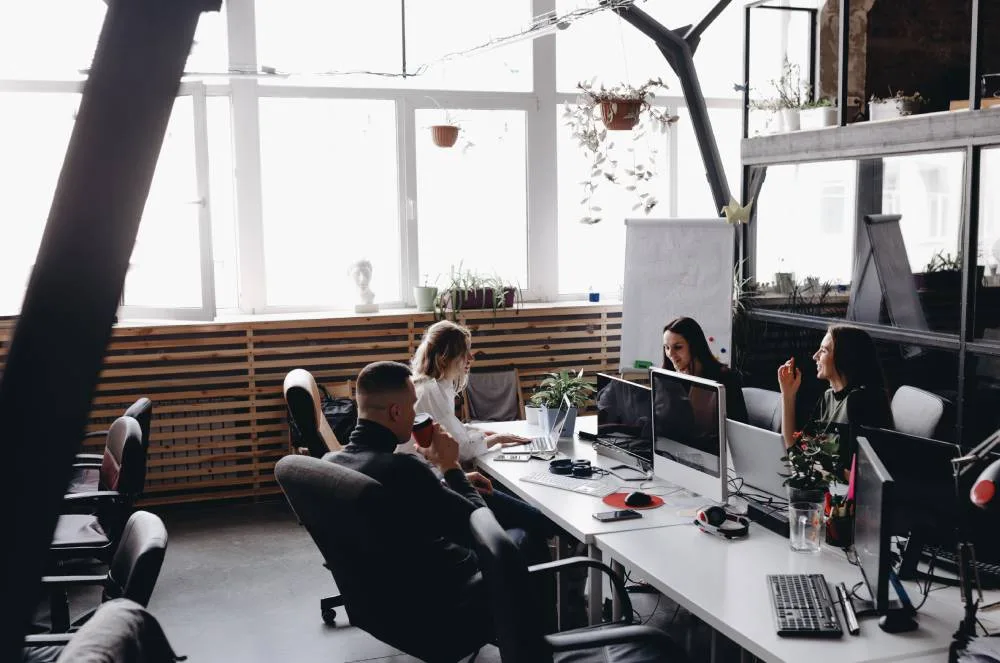 Equipo de una empresa de desarrollo de apps trabajando con ordenadores en una oficina luminosa