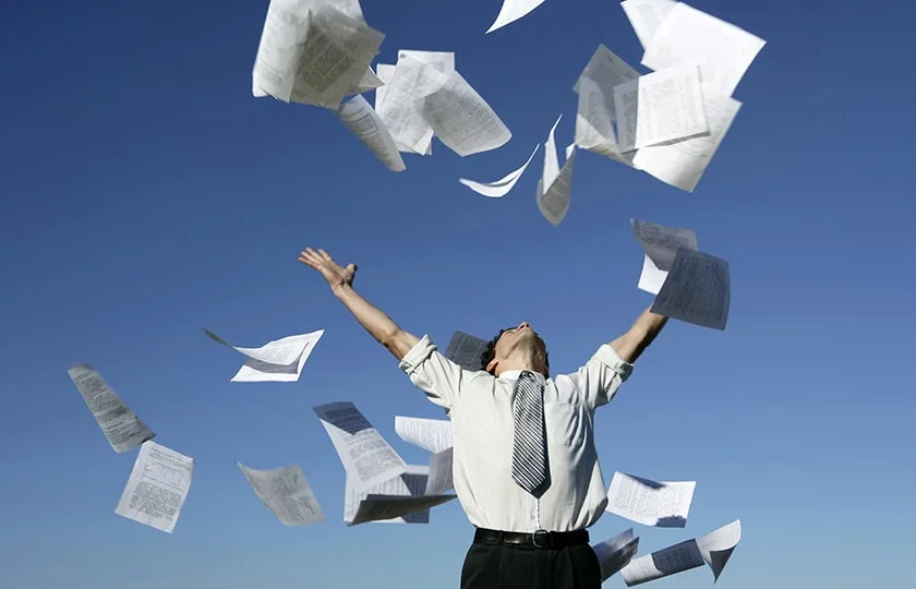 Empresario lanzando documentos al aire, caos en la gestión documental