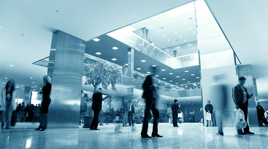 Profesionales en el vestíbulo moderno de una empresa usando dispositivos móviles