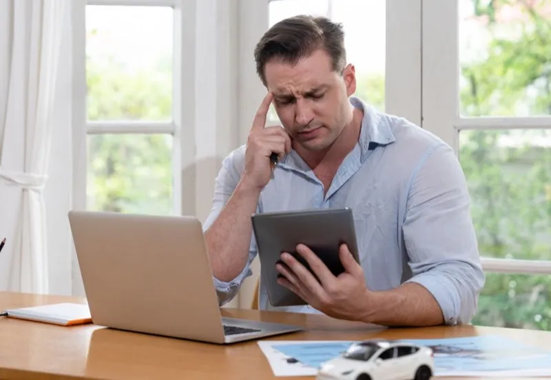 Profesional con dudas frente a un portátil y una tablet con herramientas web estándar